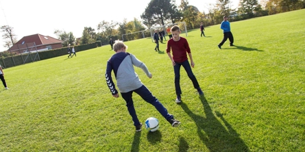 Børn spiller fodbold på plæne ved Bavnehøj Skole